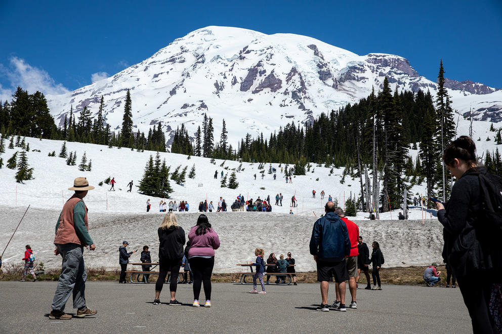 people standing at the base of a snow-covered mountain on a clear day 