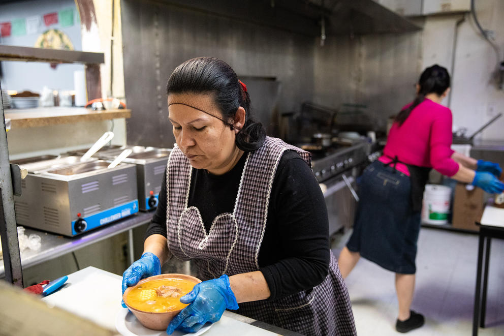 A woman prepares food in the kitchen of a Mexican restaurant. 