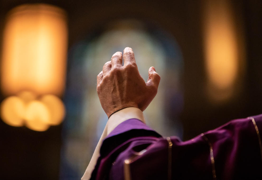 A close up of a priest's hand raised 