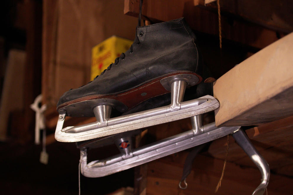 A pair of ice skates dangling from a shelf.