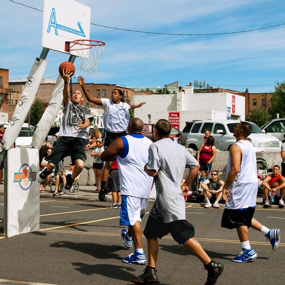 Man attempts to shoot as defender and other players watch during a game in downtown Spokane 