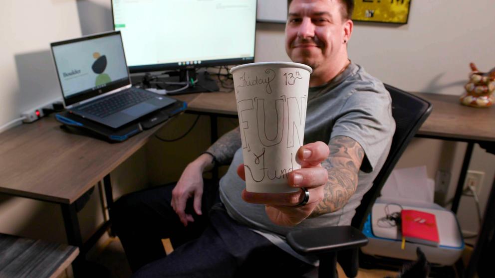 A man holds a cup with "Friday the 13th written on it."