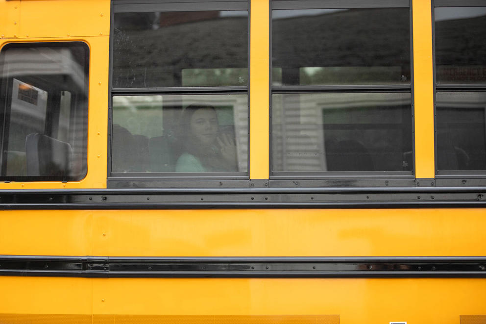 A student waves out the window of a school bus.