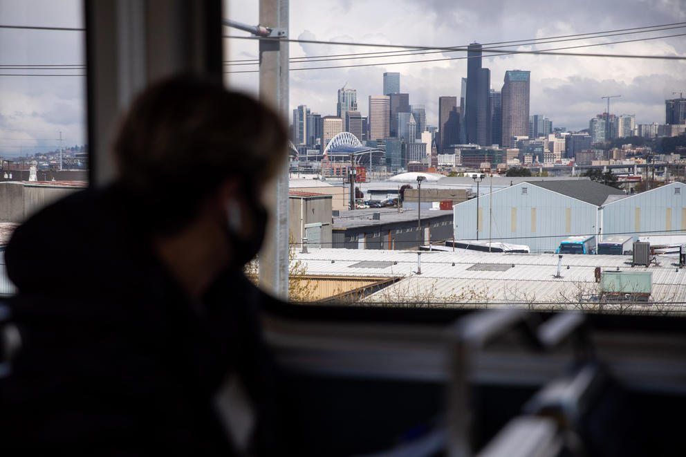 Silhouette of a person looking out at the downtown Seattle skyline from a light rail car