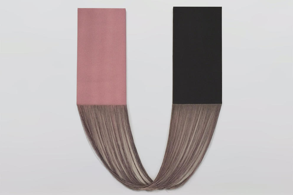 photo of a wall hanging that has two rectangles, one pink, one black, attached by long drooping threads