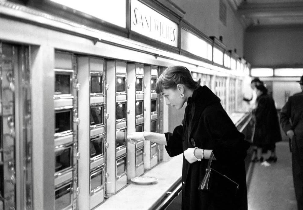 black and white photo of audrey hepburn at an automat