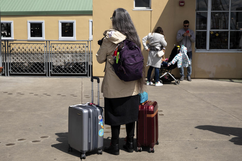 A woman faces away from camera with two suitcases on either side of her