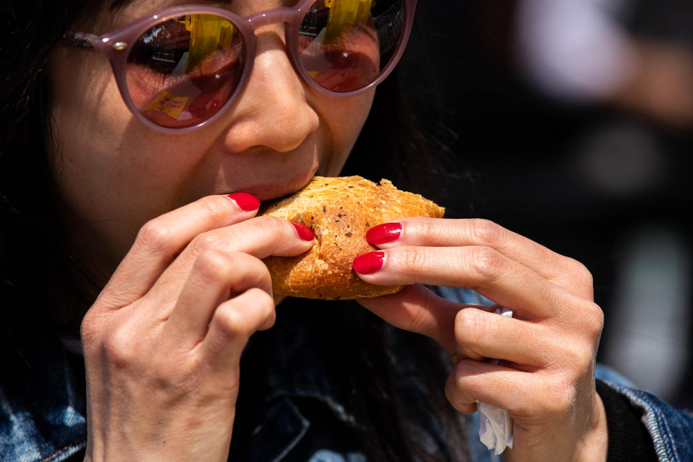 a close up of a woman taking a bite of a Piroshky