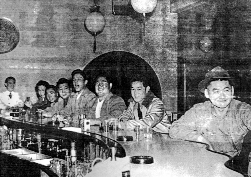 Men sit at a bar in this black and white archival photo