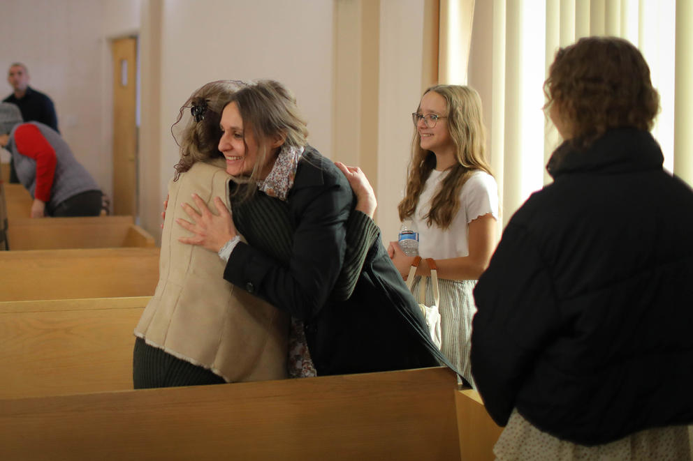 Two women hug between church pews