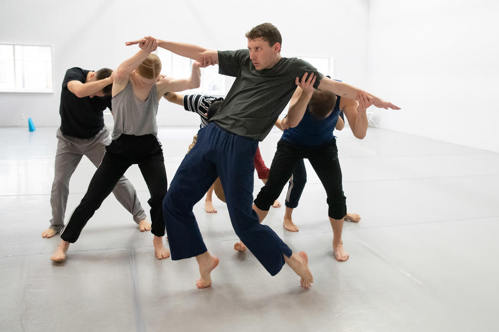 Dancers in a white room forming a group together