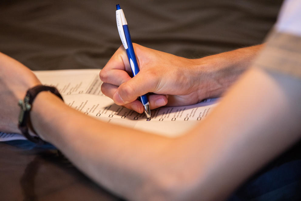Person with a pen filling out a ballot