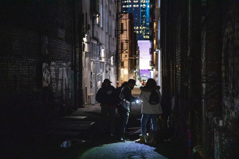 Three people in silhouette in a dark alley