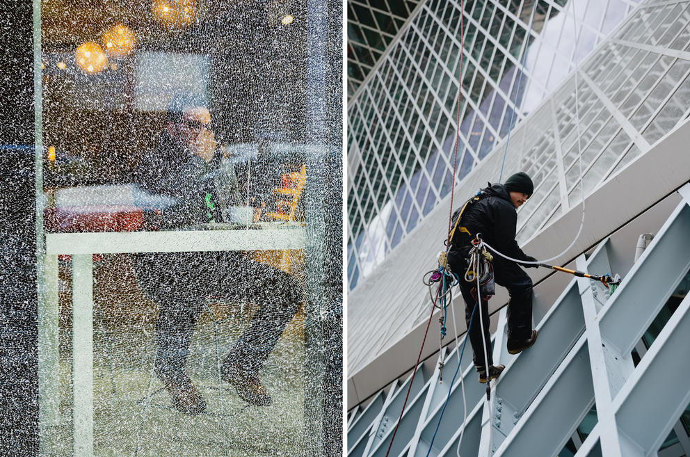a man sitting in a cafe next to a broken window and a window washer hanging off the downtown library exterior