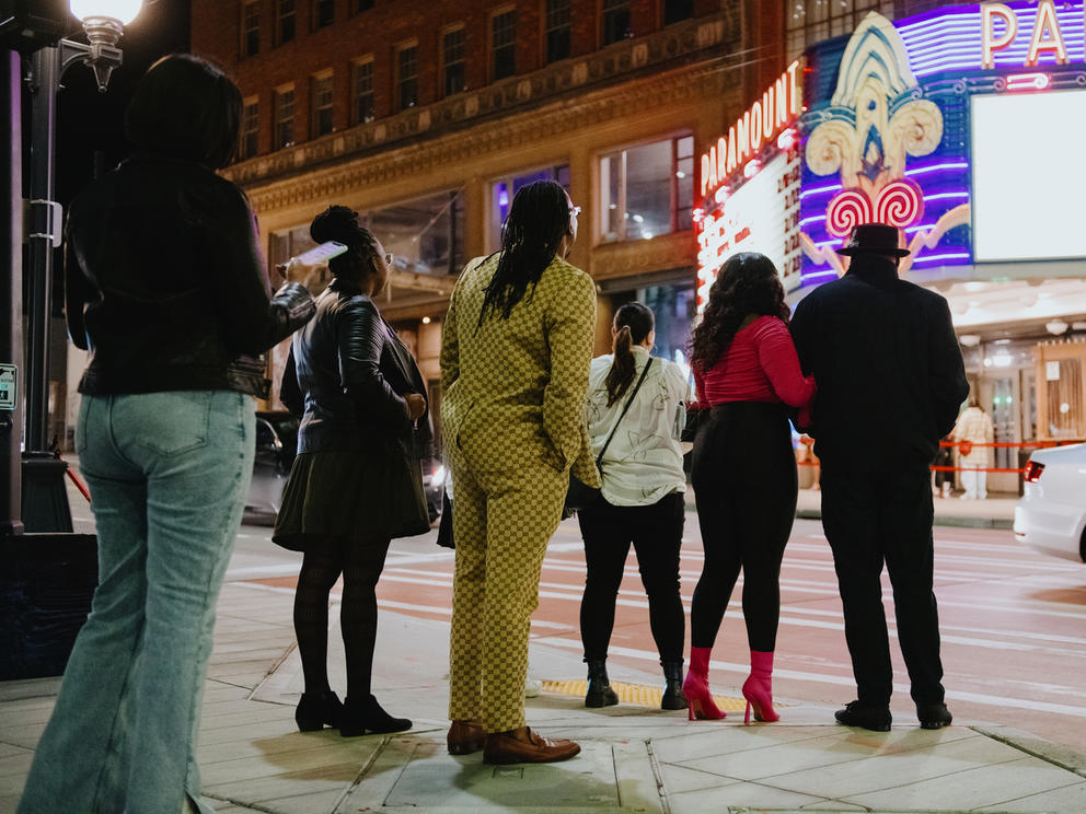A crowd stands outside the paramount theater at night