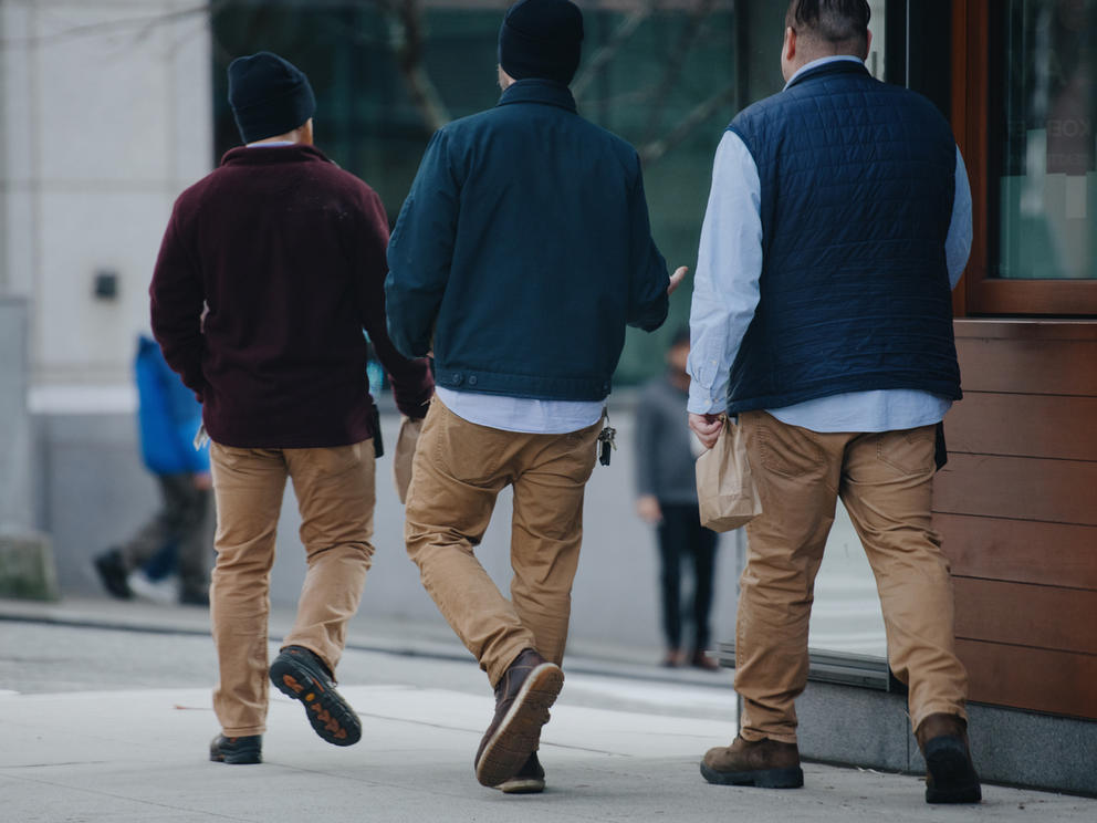 three men in matching khakis walk back to their office downtown