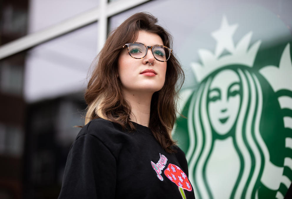 Natalie Mattera stands in front of a Starbucks logo in the window of the store where she works.