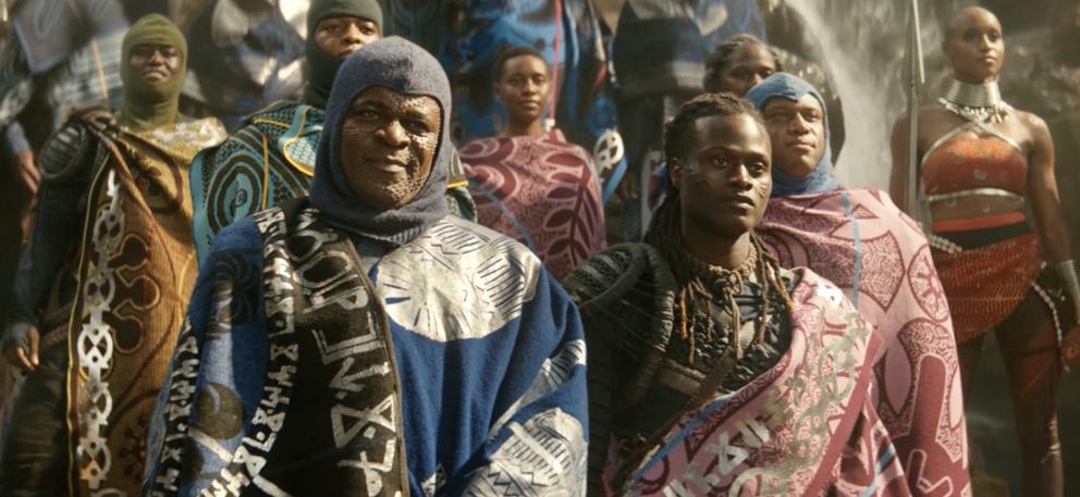 a movie still from Wakanda Forever, featuring warriors dressed in battle gear and ornate blankets