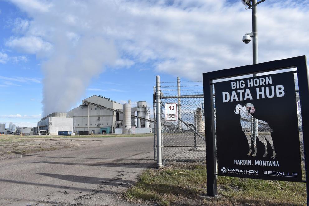 A coal-fired power plant blows smoke behind a sign of the cryptocurrency "mining" operation Big Horn Data Hub