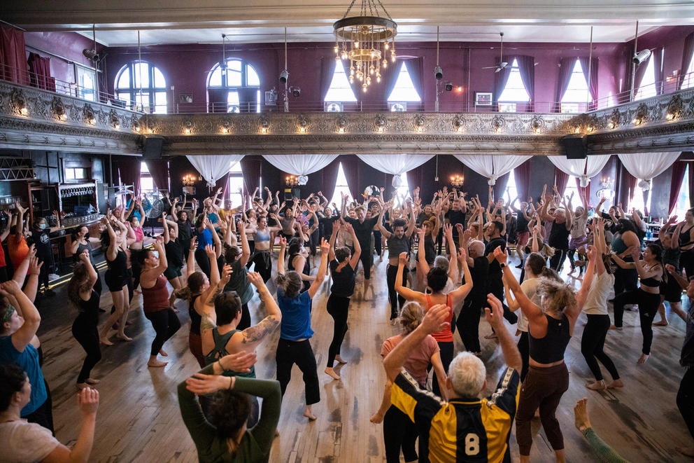 a glamorous two story ballroom filled with people dancing in exercise clothes