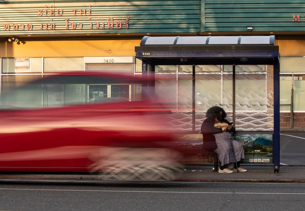 A person waits at a bus stop on the corner of Rainier Avenue South and South Walden Street 