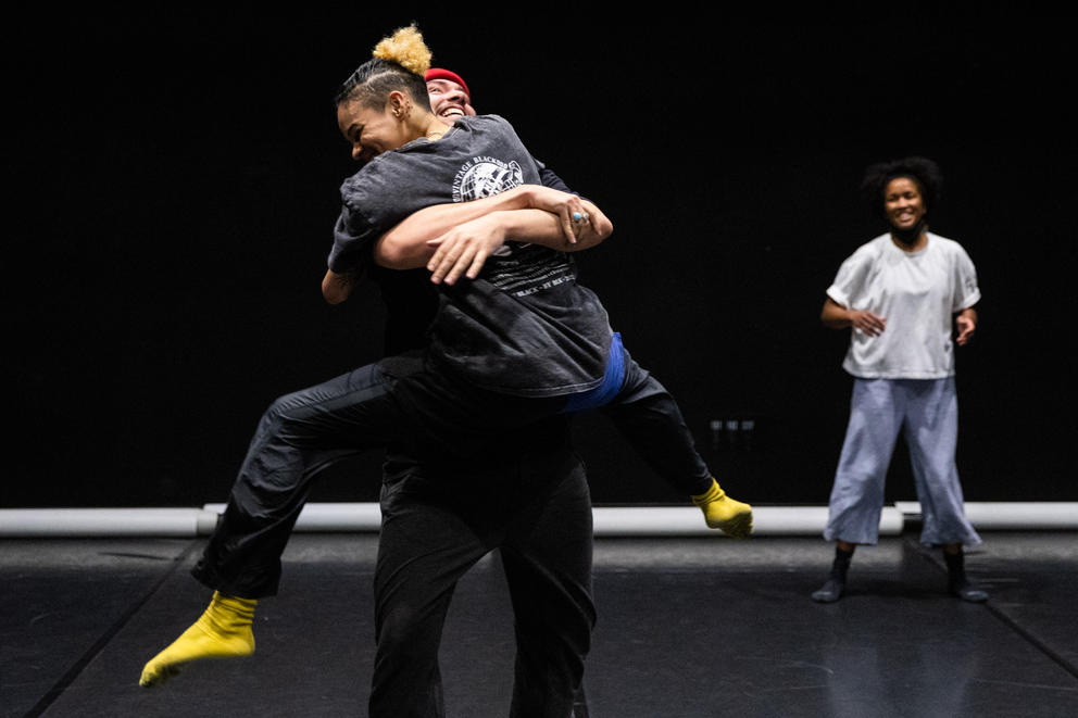dancers embrace on a black box theater stage