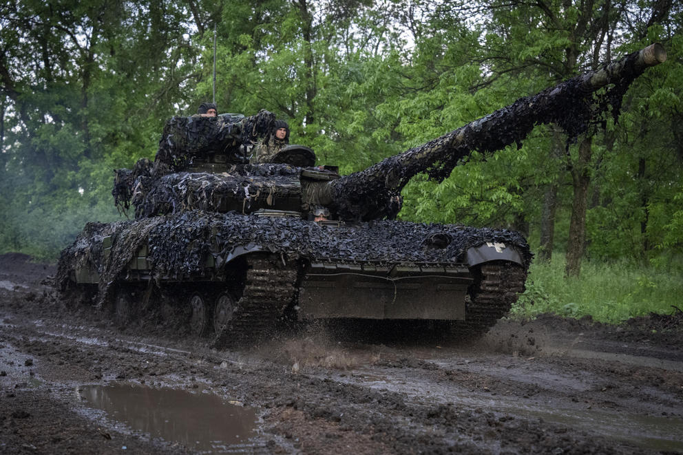 A camouflaged Ukranian tanker is driven by soldiers 