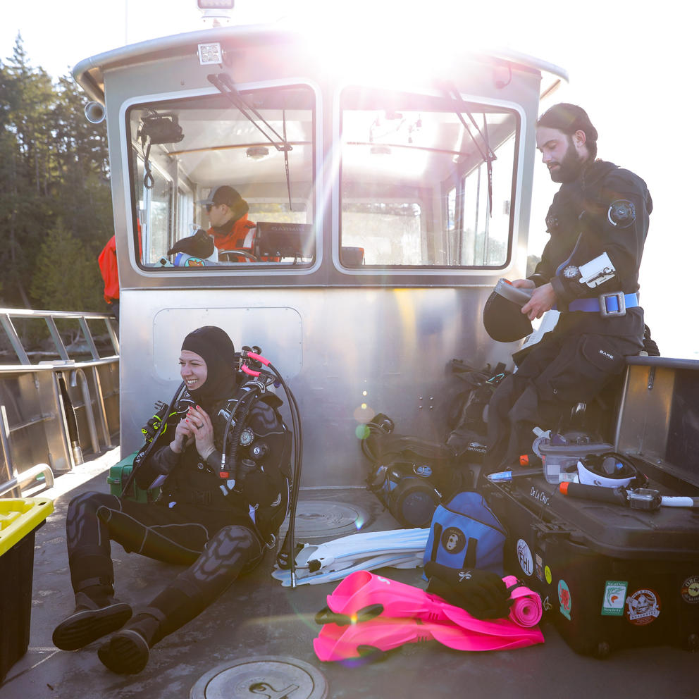two divers put on their gear on the deck of a boat