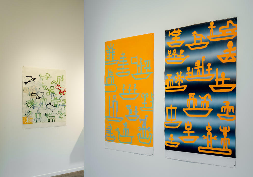 a gallery show with bright rectangular paintings with petroglyphic imagery