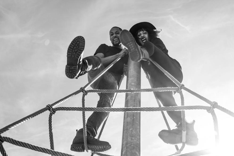 black and white photo of two people climbing on a jungle gym