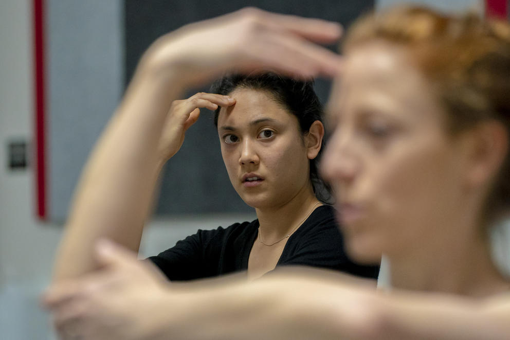 A dancer is seen through the arms of the choreographer as they learn a dance