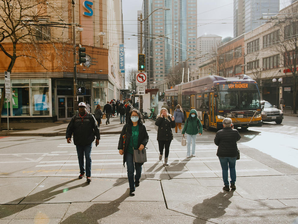 a group of people cross the street in downtown seattle surrounded by buidlings