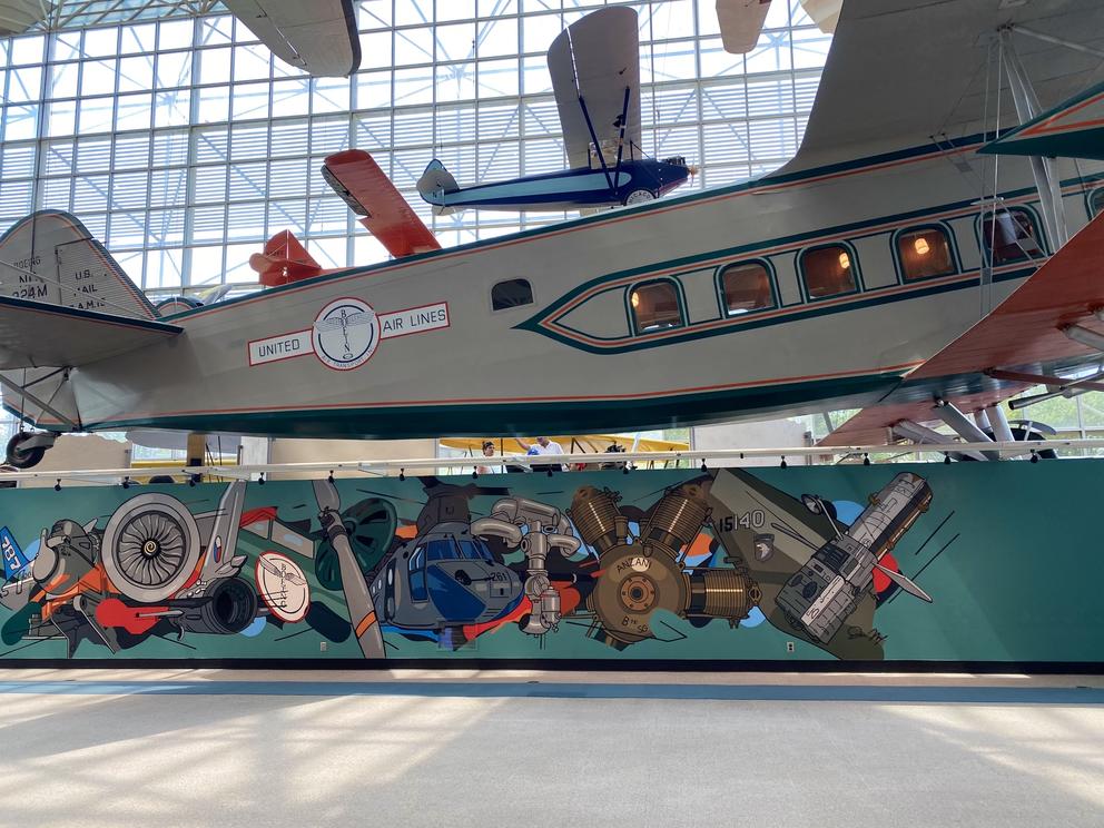 photo of a plane museum with a colorful mural below a vintage plane