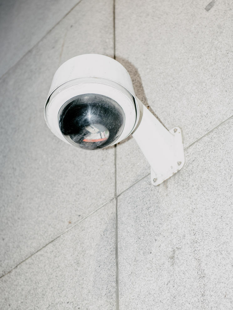 A close up on a security camera on a gray brick wall.