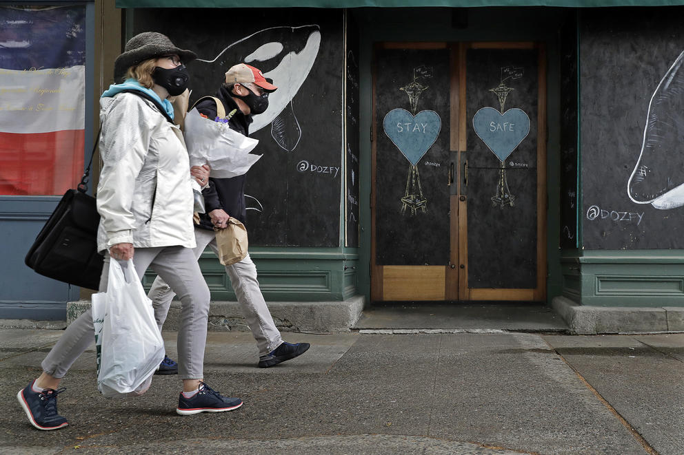 Pedestrians wearing face masks walk past art by the street artist @dozfy
