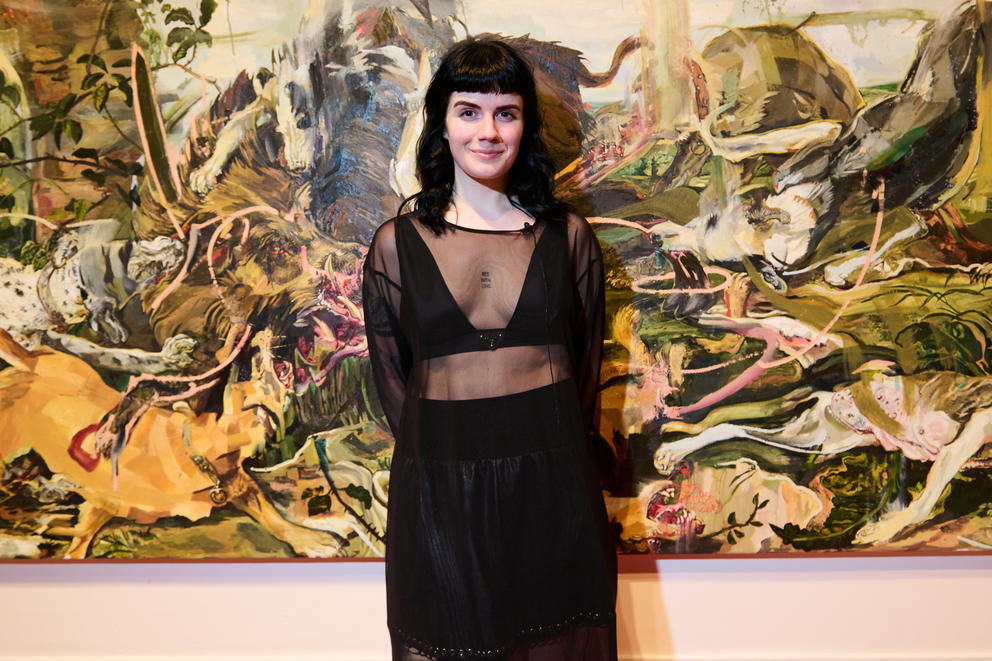a woman dressed in chic black attire stands in front of a green and yellow painting