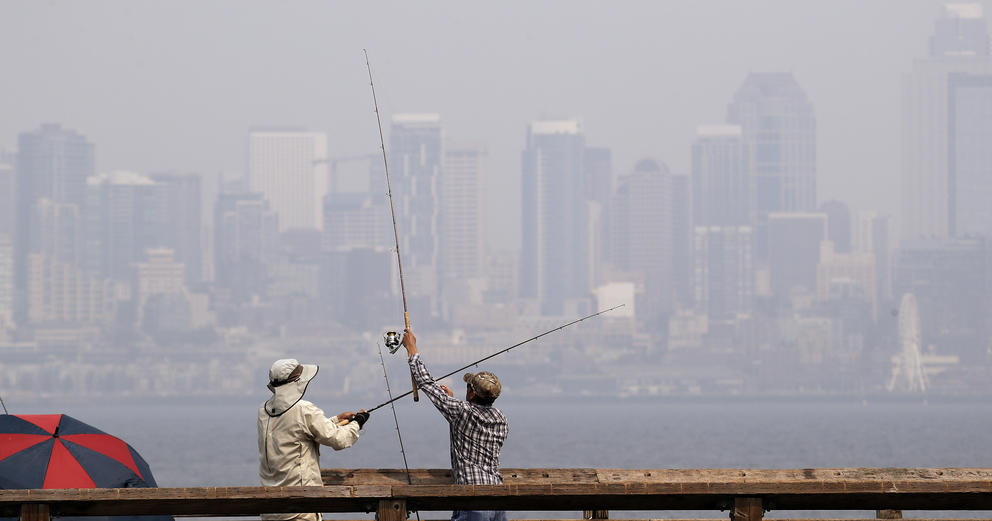 A pair of anglers uncross their lines while fishing with a city skyline in the background