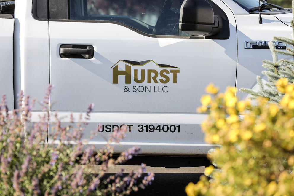 A white pickup truck with the Hurst & Son logo is parked