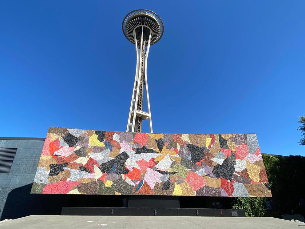 photo of a mosaic wall with the space needle behind and blue skies