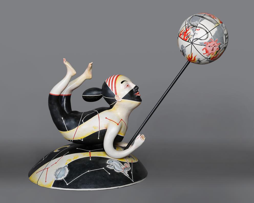 a ceramic figure of a humanoid figure painted black and white holding a burning globe on a stick