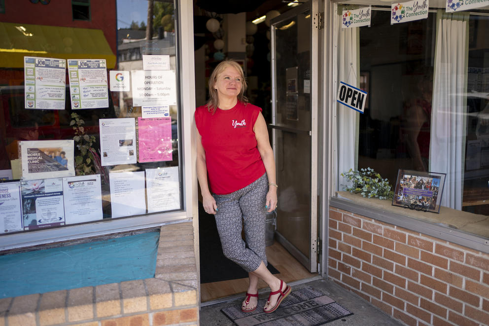 Kirchoff, wearing a red shirt, poses in the storefront doorway of The Youth Connection