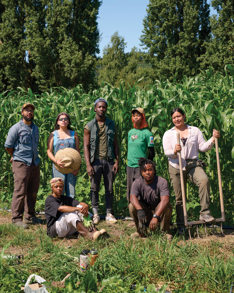A group of people pose in a group portrait in a crop field.