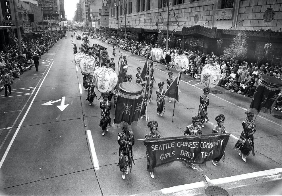 vintage black and white photo of a parade with girls marching in costume