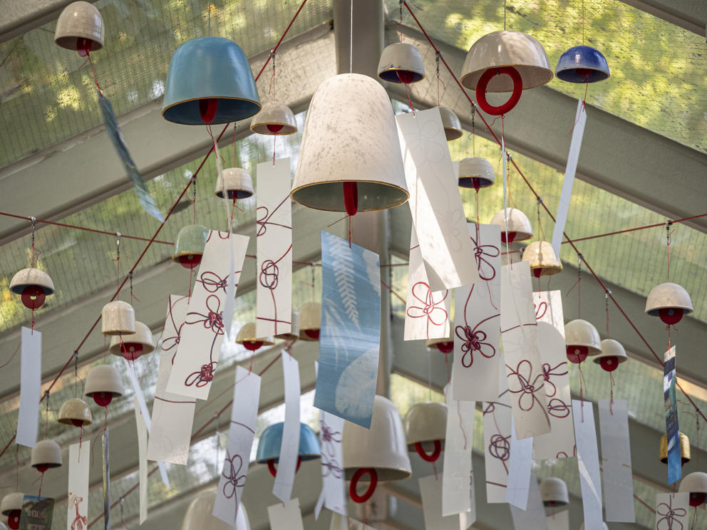 photo of ceramic wind chimes hung outside with red thread