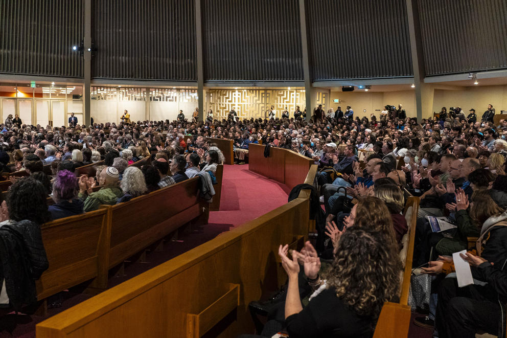A crowd of people sits during a service at a synagogue