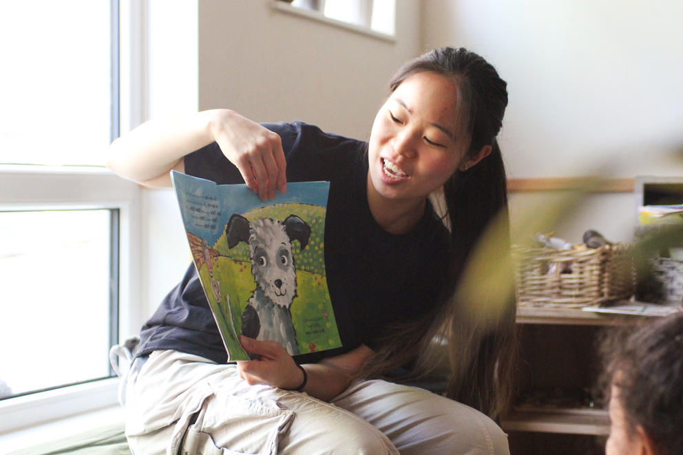 An adult shows a children's book to an unseen audience.