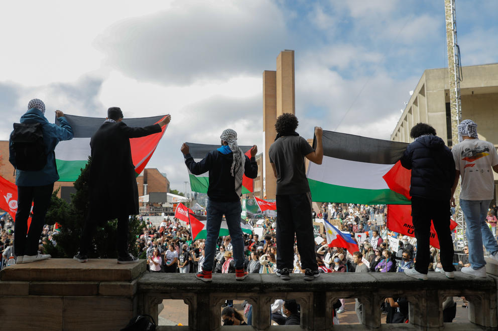 People hold Palestinian flags above a crowd