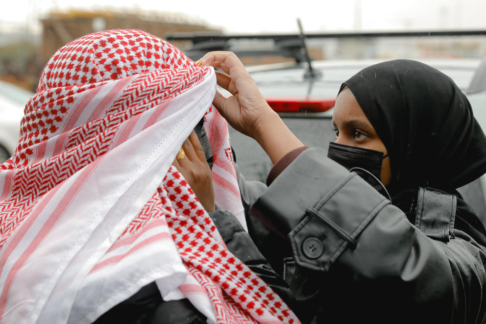 A woman helps her friend put on her keffiyeh during the protest at the Port of Tacoma.