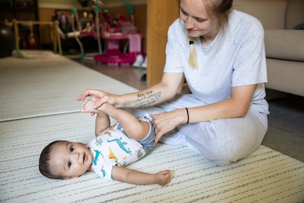 Paige Zorn plays with her baby Zaylin on the floor in the playroom