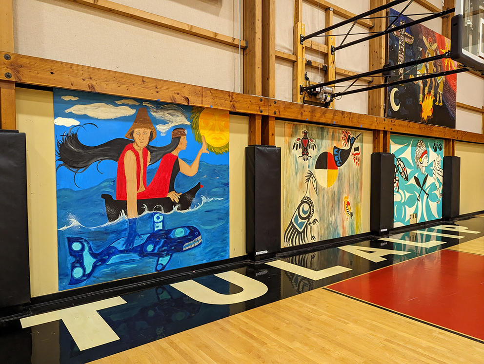 Colorful murals adorn the interior walls of a gymnasium.